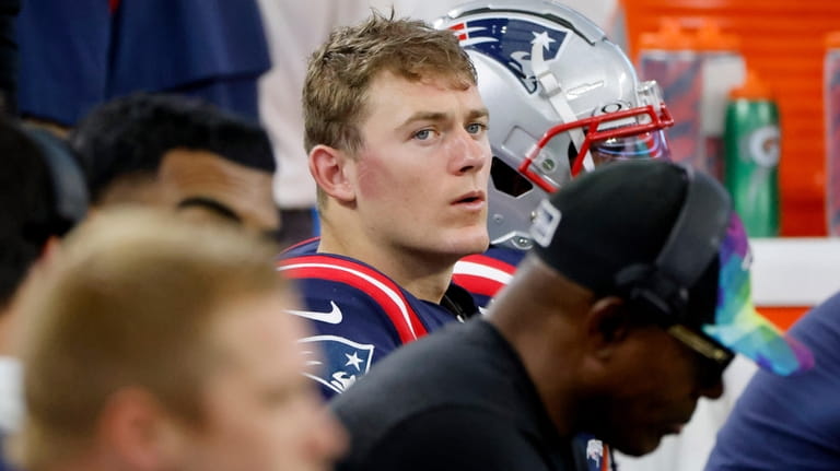 New England Patriots quarterback Mac Jones sits on the bench...
