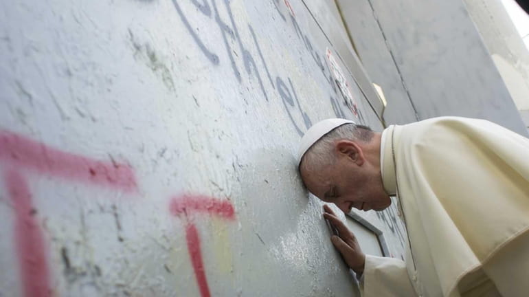 Pope Francis prays at Israel's separation barrier on May 25,...