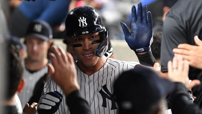 The Yankees' Aaron Judge is greeted in the dugout after...