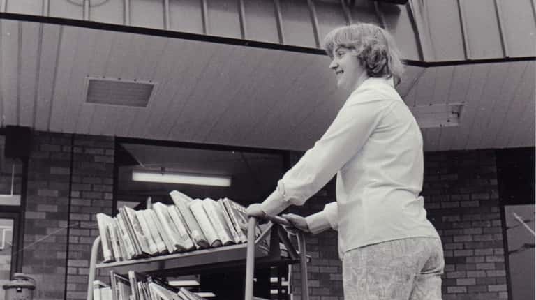 An employee wheels a cartload of books toward the new Shirley community library...