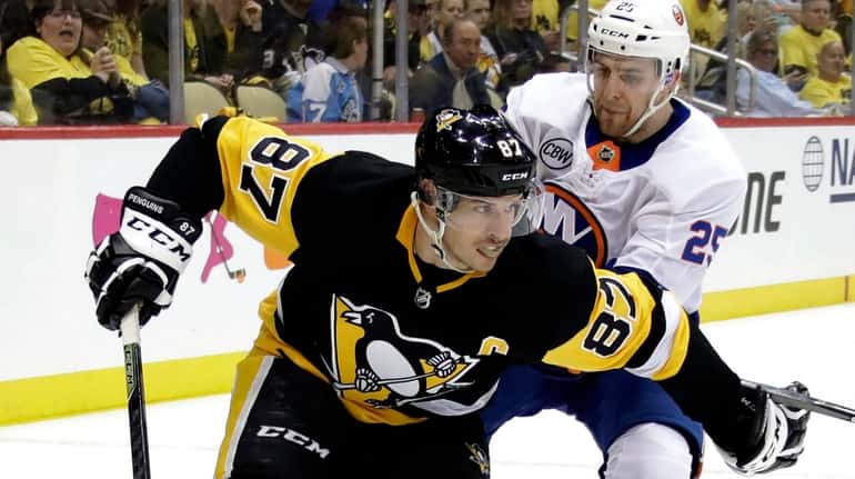 Pittsburgh Penguins' Sidney Crosby (87) holds off Islanders' Devon Toews...