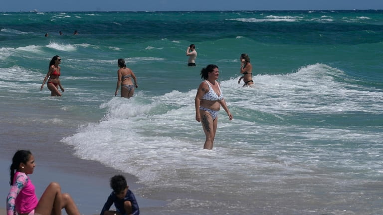 Beachgoers stay close to shore as choppy waves caused by...