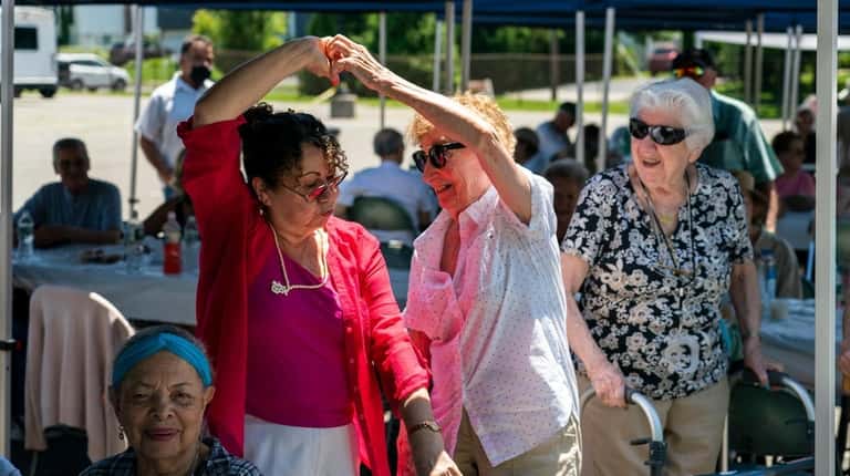 Rosa Farfan, 75, left, and Estele Diaz, 86, dance at...