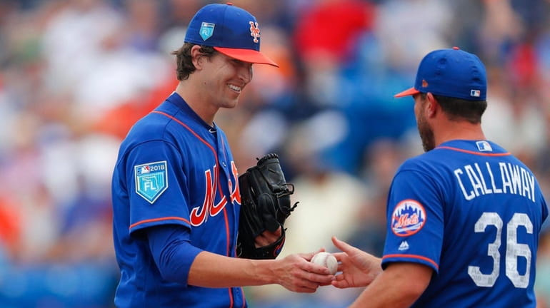 Mets starting pitcher Jacob deGrom hands the ball to manager...