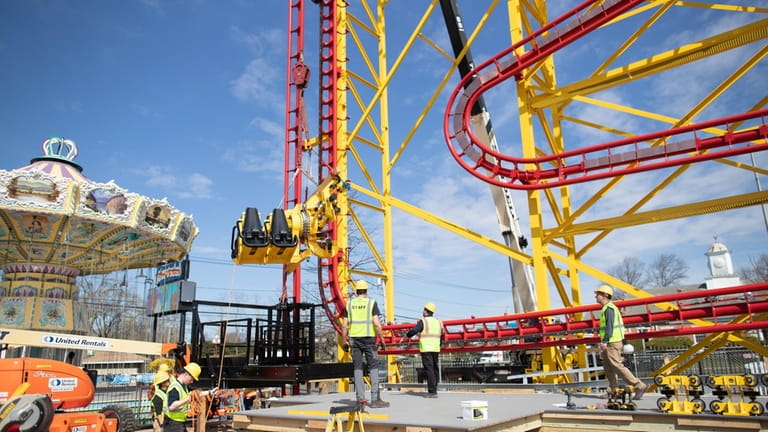 A crane lowers a roller coaster car during the construction...