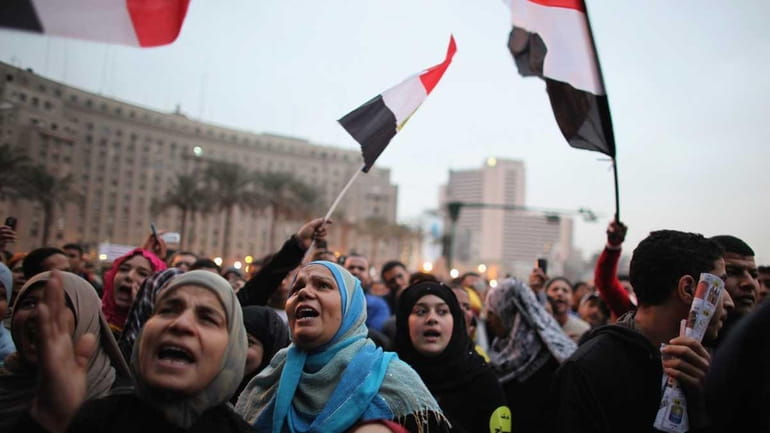People wave flags as they gather in Tahir Square in...