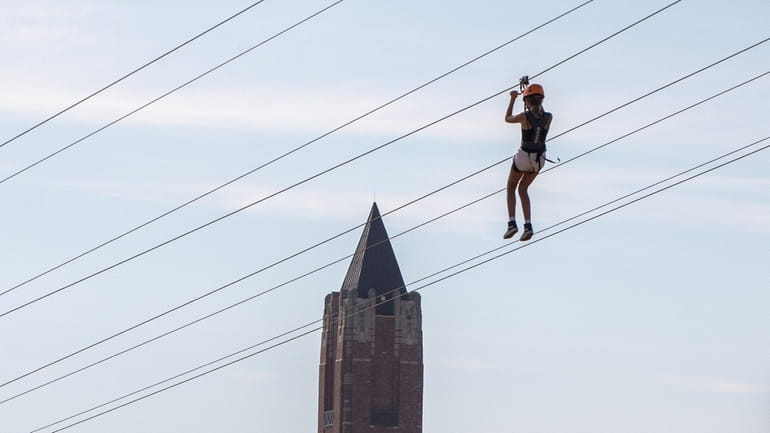 A zipliner glides down a cable at WildPlay Jones Beach...