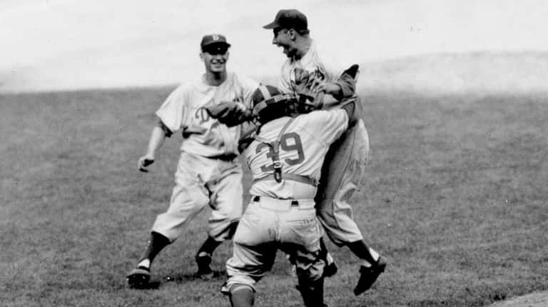 Brooklyn Dodgers pitcher Johnny Podres is lifted by catcher Roy...