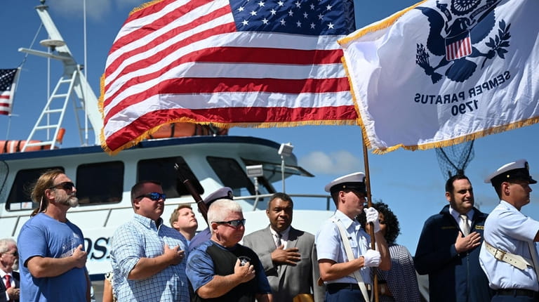 Captain James Schneider, left, holds a flag honoring a friend...