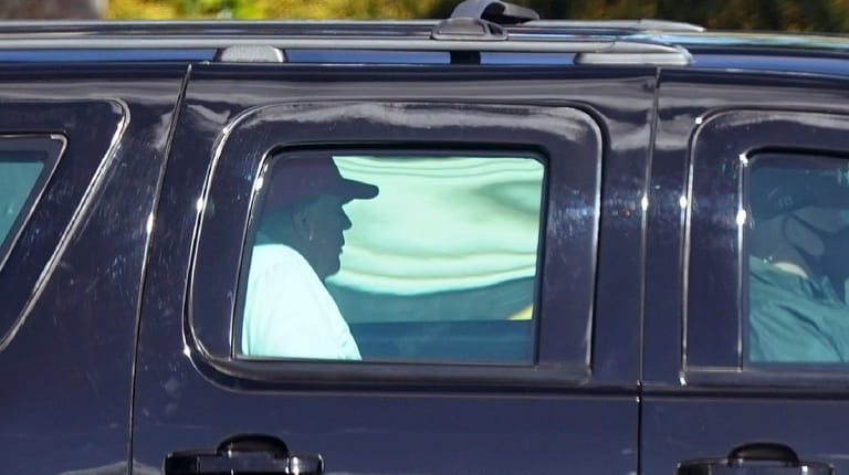 President Donald Trump rides in a motorcade vehicle as he...