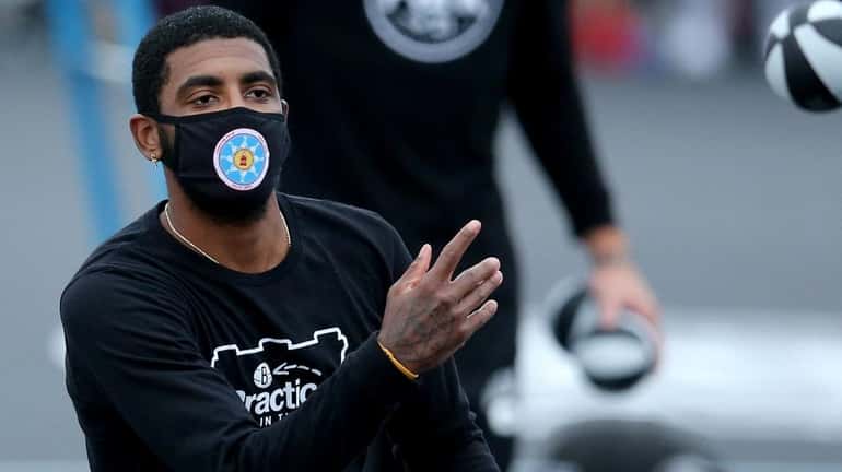 Brooklyn Nets guard Kyrie Irving tosses autographed mini basketballs into the...