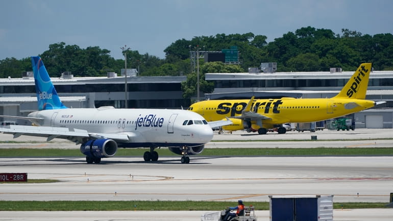A JetBlue Airways Airbus A320, left, passes a Spirit Airlines...