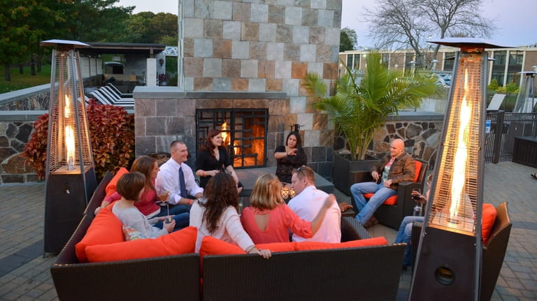 Guests gather to sip drinks and socialize around the outdoor...
