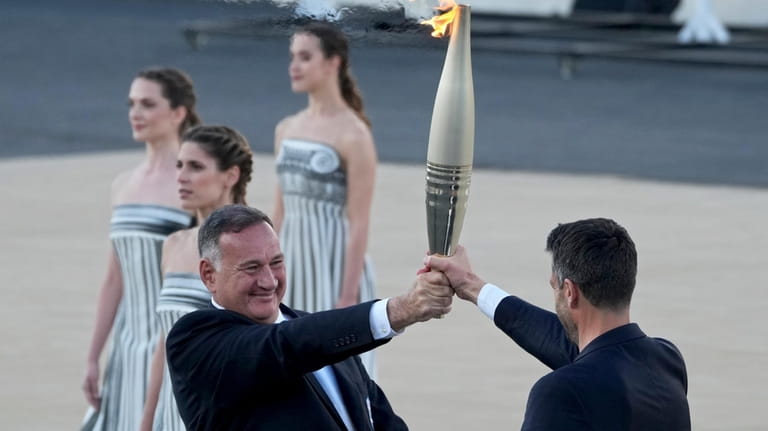 Tony Estanguet, President of Paris 2024, right, receives the Olympic...