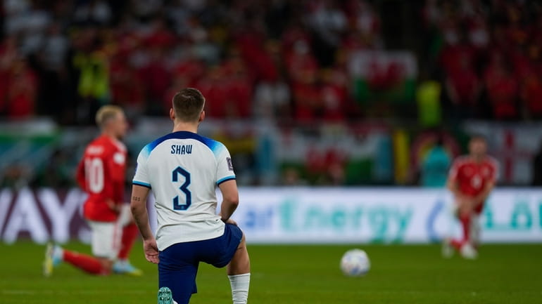 England's Luke Shaw knees along Wales players, background, just before...