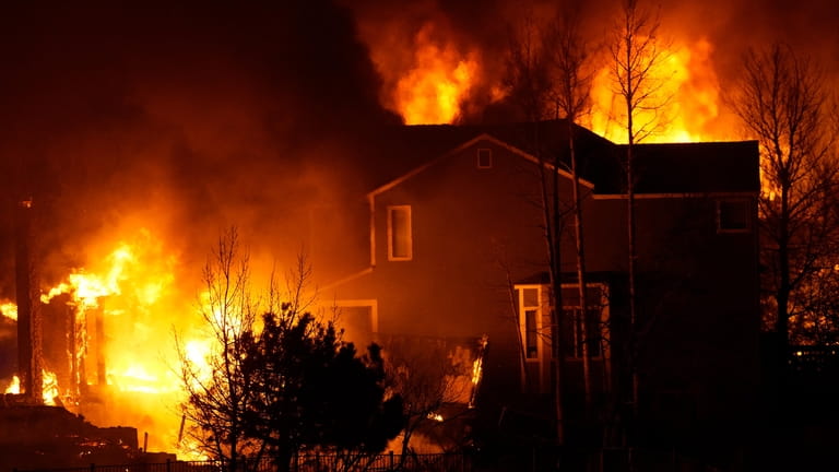 FILE — Homes burn as a wildfire rips through a...