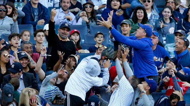 Fans try to catch a foul ball during a baseball...