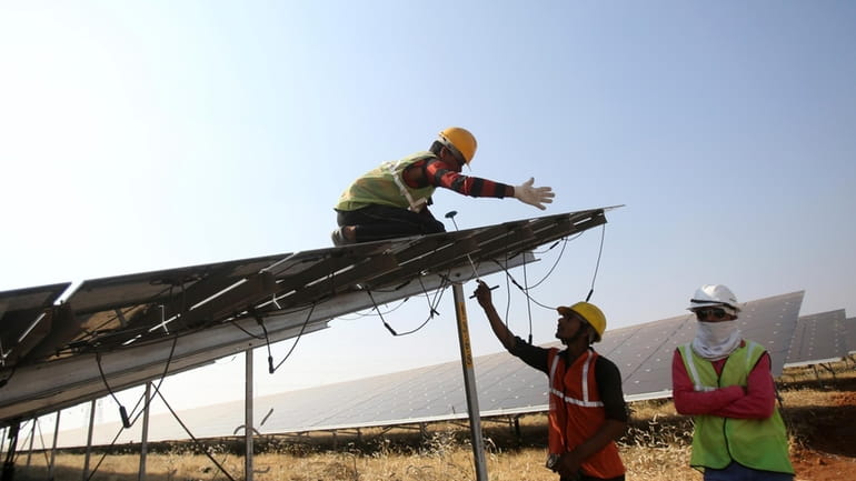 Workers install solar panels at the Pavagada Solar Park 175...