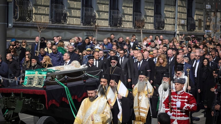Orthodox clergy, official, honour guards and people walk along with...