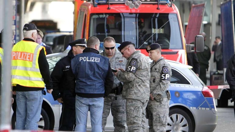 German police and US soldiers talk after a gunman fired...