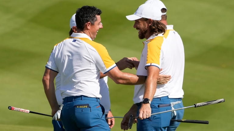 Europe's Rory Mcilroy, left shakes hands with Europe's Tommy Fleetwood...