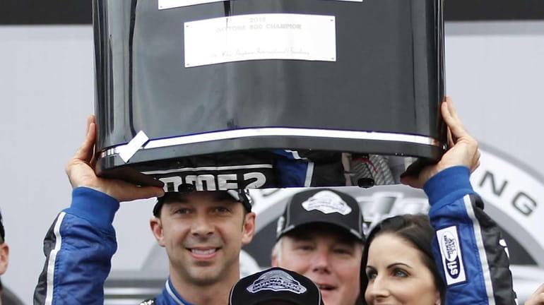 Jimmie Johnson holds up the trophy in Victory Lane after...