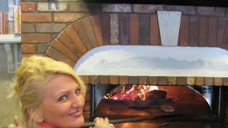Patrizia Colatosi takes bread out of the wood-burning brick oven...