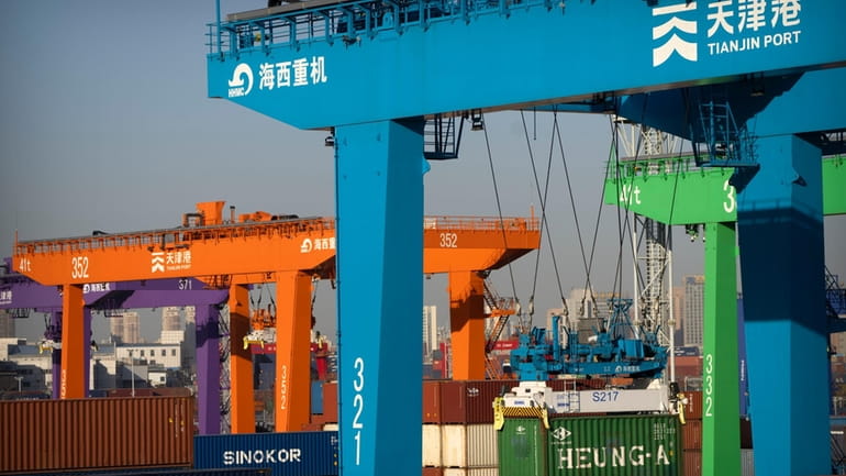File - A crane lifts a shipping container at an...