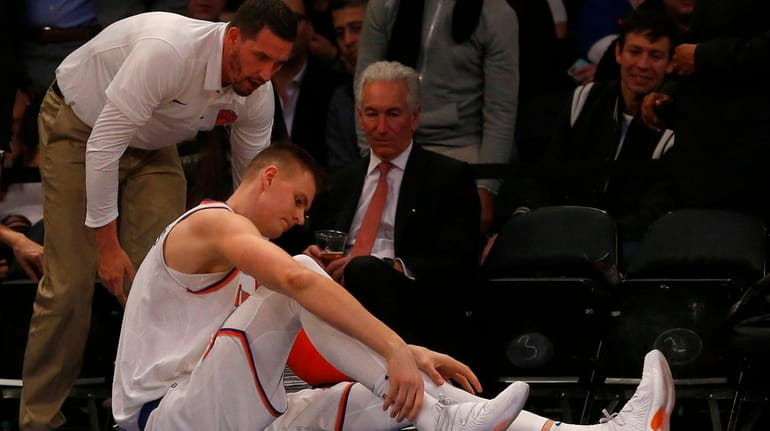 Kristaps Porzingis of the Knicks grabs his right ankle after...