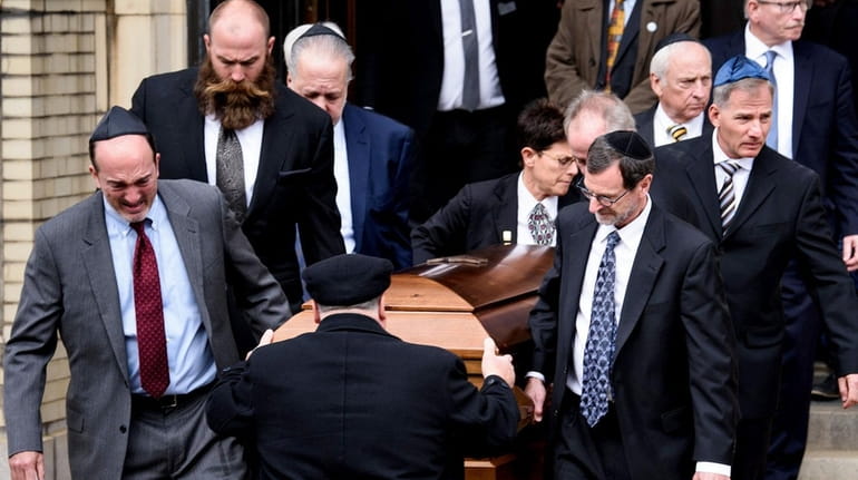 Pallbearers carry a casket from Rodef Shalom Congregation following the...
