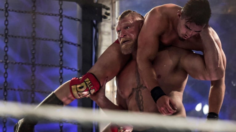 Brock Lesnar carries Austin Theory as they wrestle during the...