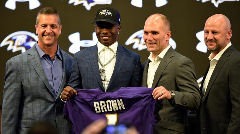 Ravens first-round draft pick Marquise Brown, center, stands with head...