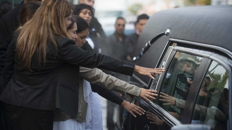 Relatives of Christopher Khan reach out to the hearse carrying...