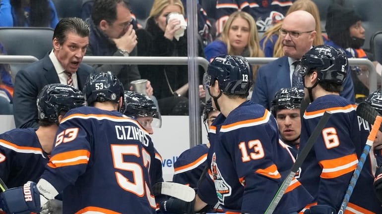 Islanders head coach Lane Lambert, left, talks to his team...
