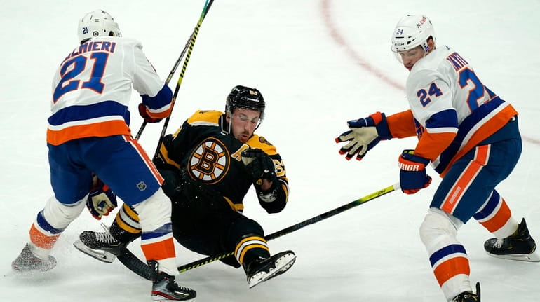 Bruins center Brad Marchand, center, is dumped to the ice...