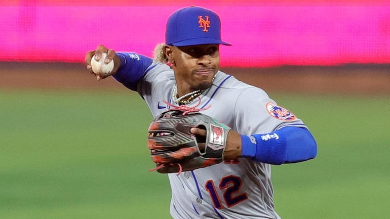 Francisco Lindor of the Mets throws for an out at first base...