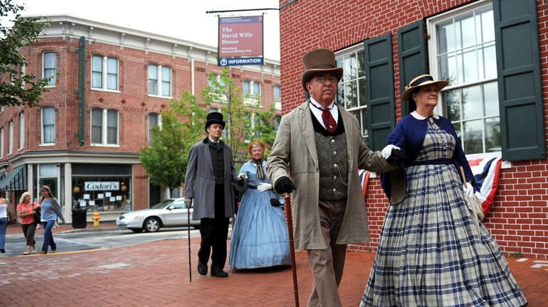 Re-enactors dressed in Civil War period clothing walk through the...