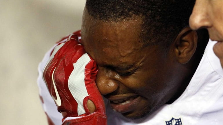 New York Giants' Victor Cruz covers his face after getting...