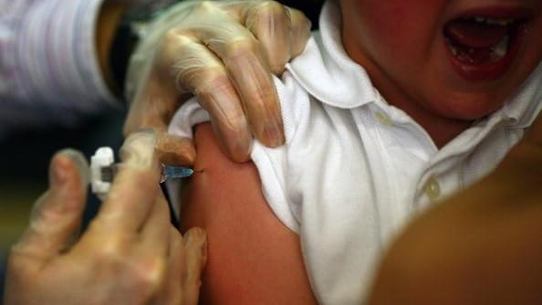 A young boy receives an immunization shot at a health...
