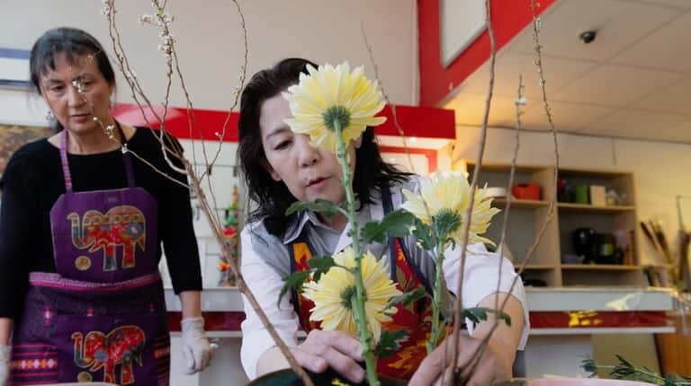 Ikebana instructor Toyomi Sobue, right, helps Alma Davis-Carlin with her flower...