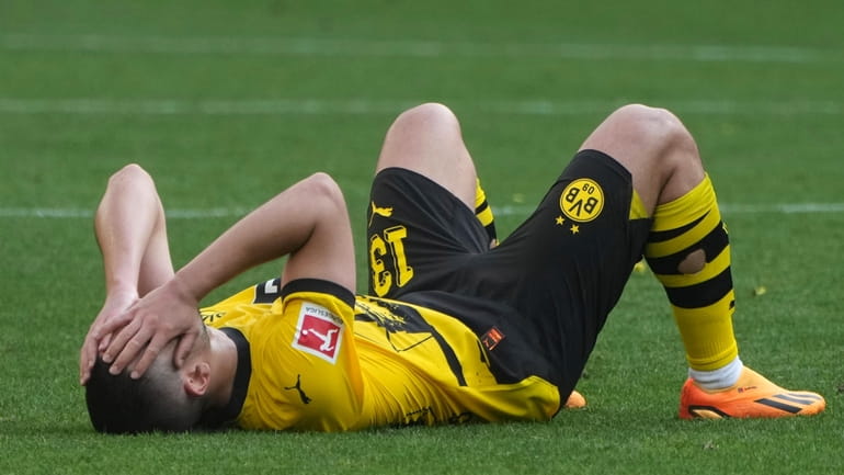 Dortmund's Raphael Guerreiro covers his face after the German Bundesliga...