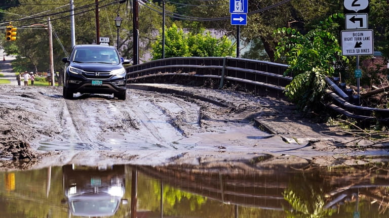 A driver stops on a mud-covered bridge while deciding whether...