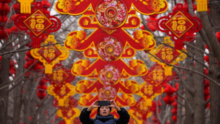A woman takes a picture of red lanterns and decorations...
