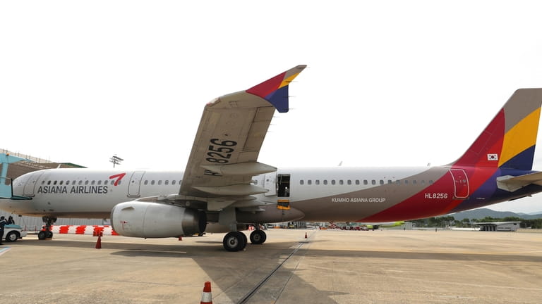 An Asiana Airlines plane is parked as one of the...