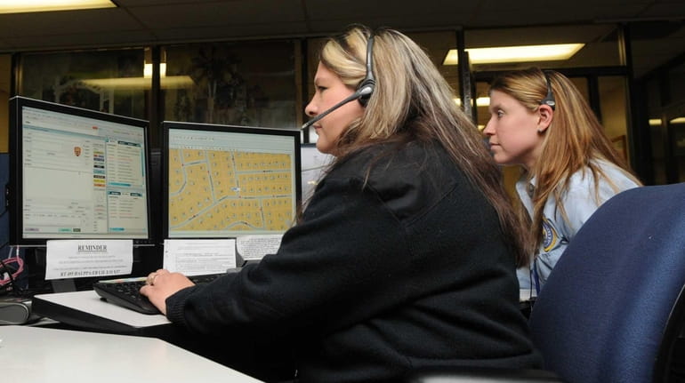 Suffolk County police 911 dispatchers work the phones at the...