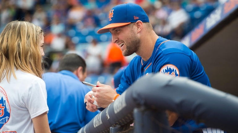 Tim Tebow signs a ball for Mackenzie Demers, 12, of...