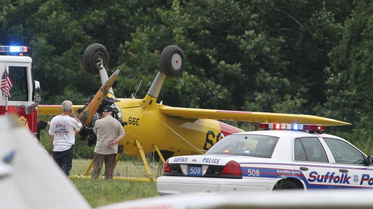 People look at a small plane that flipped over at...