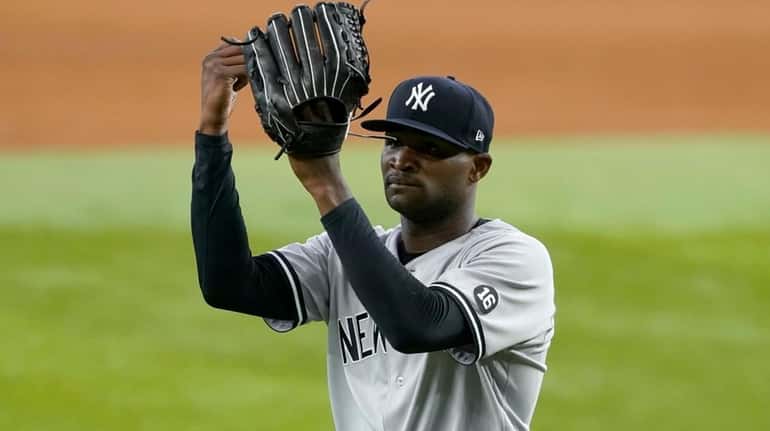 Yankees starting pitcher Domingo German taps his glove as he...