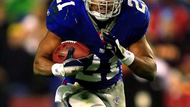 Tiki Barber runs the ball during a game against the...