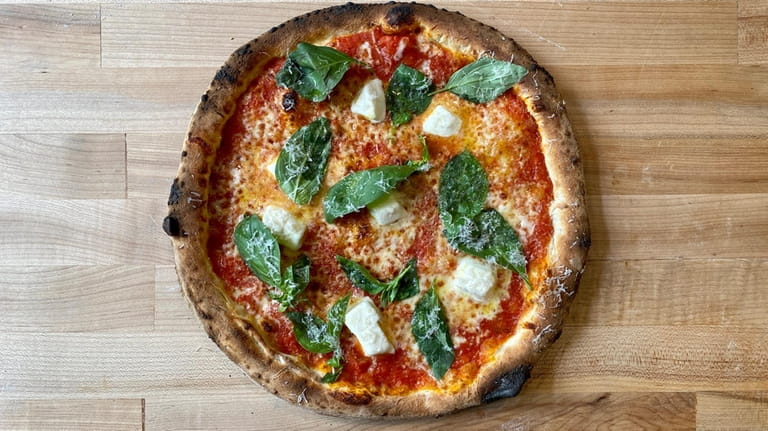 The Margherita pizza is cooked in a wood-fired oven at...